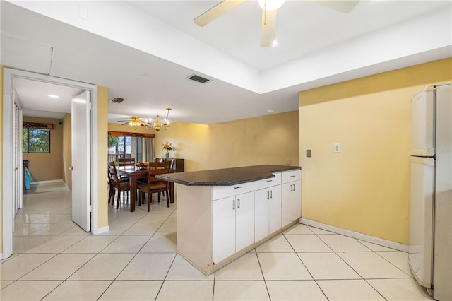 kitchen with white cabinetry, light tile patterned floors, kitchen peninsula, and white fridge