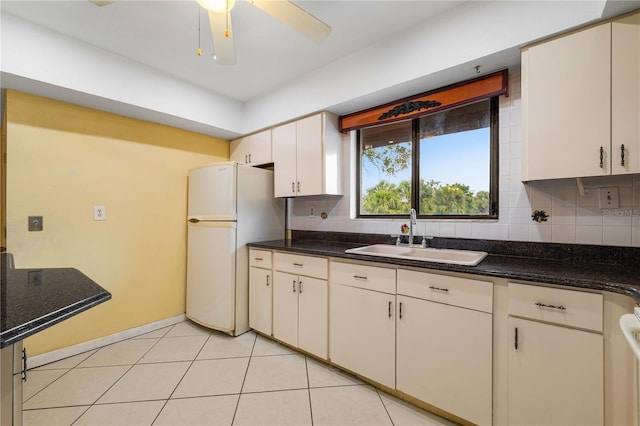 kitchen with light tile patterned flooring, sink, white cabinets, backsplash, and white fridge