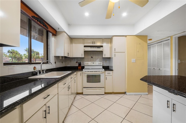 kitchen featuring white electric stove, sink, dark stone counters, decorative backsplash, and cream cabinets