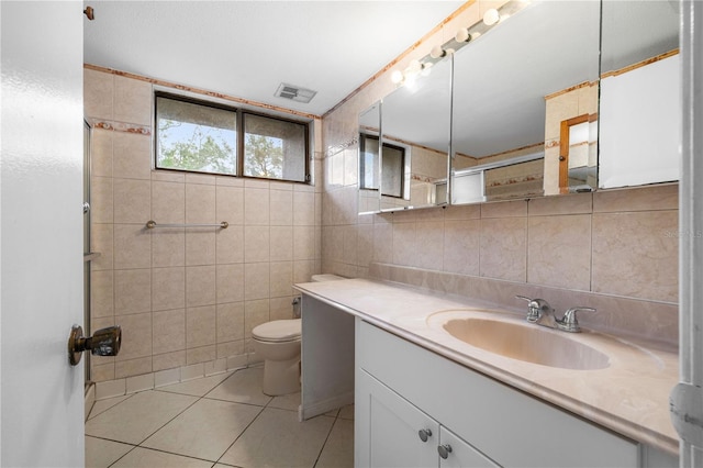 bathroom with tile patterned flooring, vanity, tile walls, and toilet