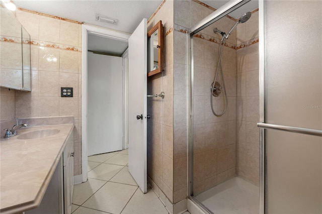 bathroom with tile patterned flooring, vanity, a shower with door, and tile walls