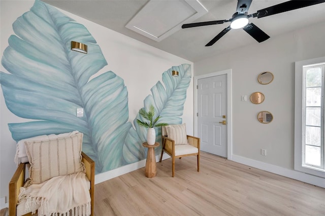 living area featuring light wood finished floors, plenty of natural light, attic access, and baseboards