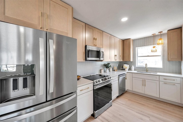 kitchen with decorative light fixtures, stainless steel appliances, tasteful backsplash, light countertops, and a sink