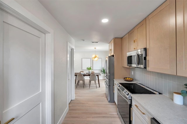 kitchen featuring pendant lighting, stainless steel appliances, light countertops, and light brown cabinetry