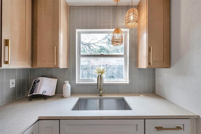 kitchen with tasteful backsplash, light countertops, a sink, and decorative light fixtures