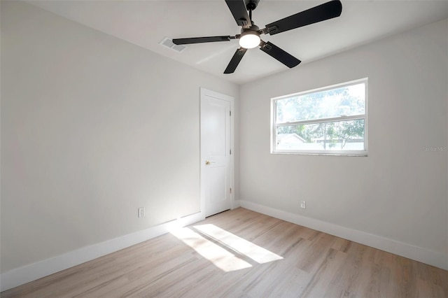 spare room featuring light wood-type flooring, visible vents, and baseboards