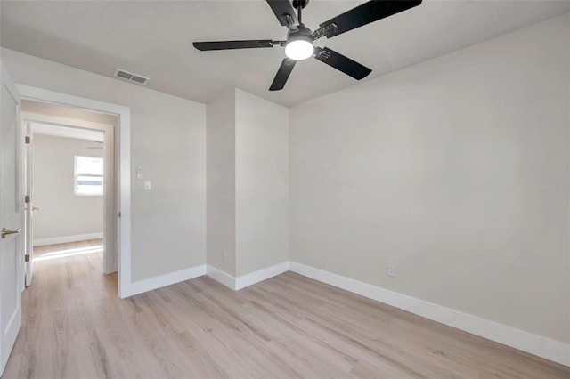 empty room featuring light wood-style flooring, visible vents, and baseboards