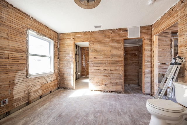 unfurnished room featuring a textured ceiling and wood walls