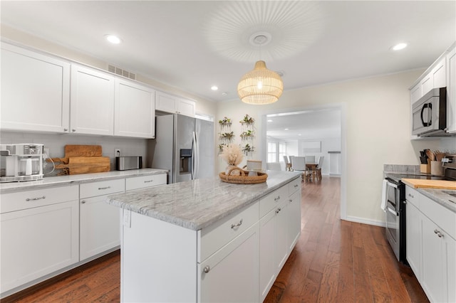 kitchen with pendant lighting, dark wood-type flooring, appliances with stainless steel finishes, white cabinetry, and a kitchen island