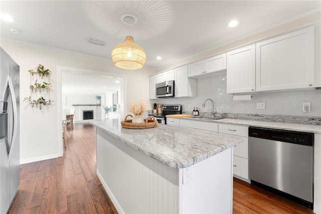 kitchen with sink, white cabinetry, decorative light fixtures, dark hardwood / wood-style flooring, and stainless steel appliances