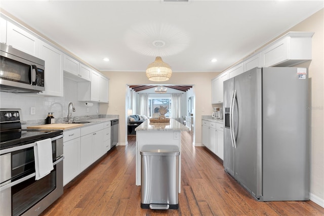 kitchen with stainless steel appliances, hanging light fixtures, dark hardwood / wood-style floors, and white cabinets