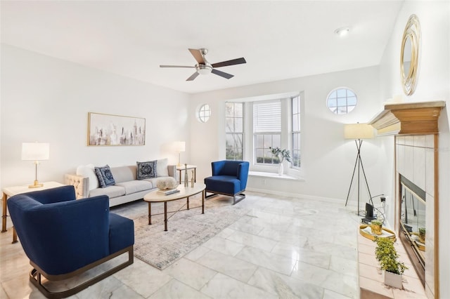 living room featuring a tile fireplace and ceiling fan