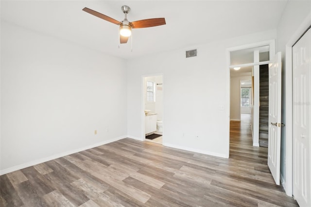 unfurnished bedroom with connected bathroom, hardwood / wood-style flooring, a closet, and ceiling fan