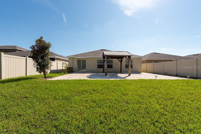 rear view of property featuring a gazebo, a lawn, and a patio area