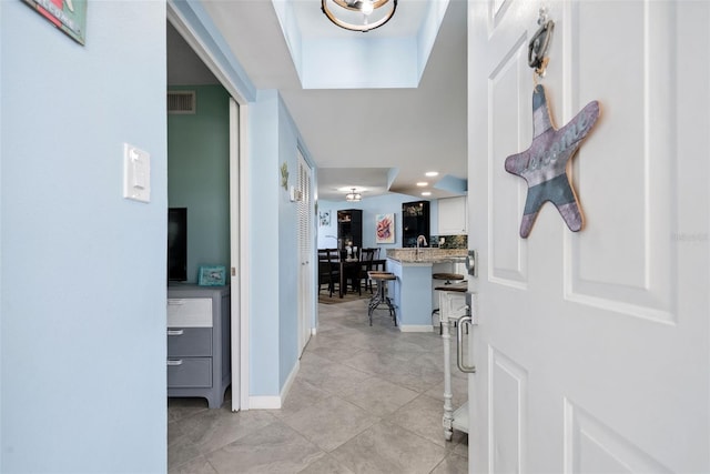 corridor featuring recessed lighting, visible vents, light tile patterned flooring, a sink, and baseboards