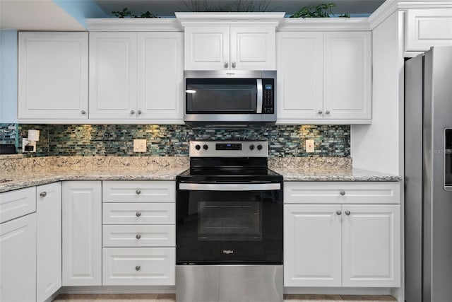 kitchen with stainless steel appliances, white cabinetry, light stone counters, and decorative backsplash