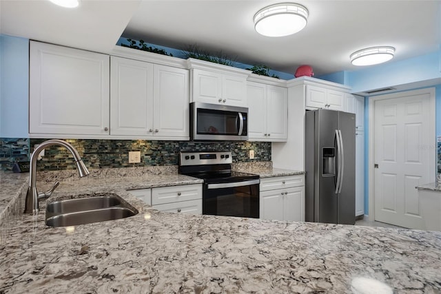 kitchen featuring stainless steel appliances, a sink, white cabinetry, and decorative backsplash