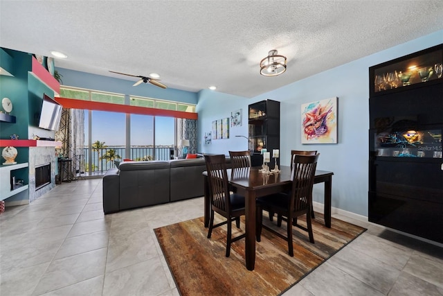 dining space featuring light tile patterned flooring, a fireplace, a textured ceiling, and baseboards