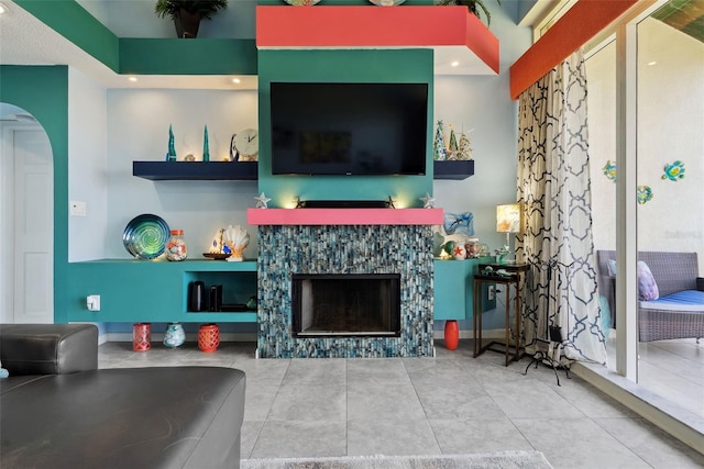 living area featuring arched walkways, a fireplace, and tile patterned floors