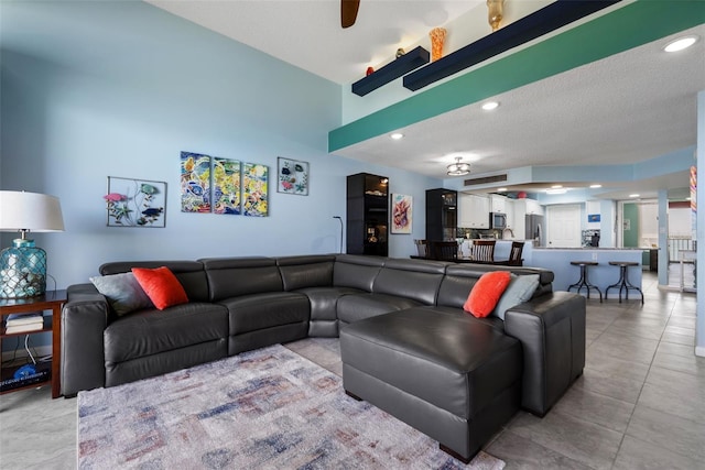 living area with light tile patterned floors, ceiling fan, a textured ceiling, and recessed lighting