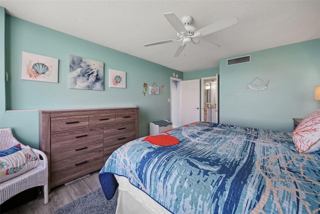 bedroom with a textured ceiling, wood finished floors, visible vents, and a ceiling fan