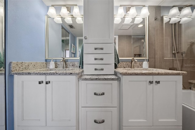 full bath featuring walk in shower, two vanities, a sink, and visible vents