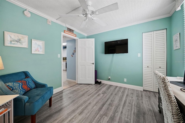 living area with ornamental molding, visible vents, a textured ceiling, and wood finished floors