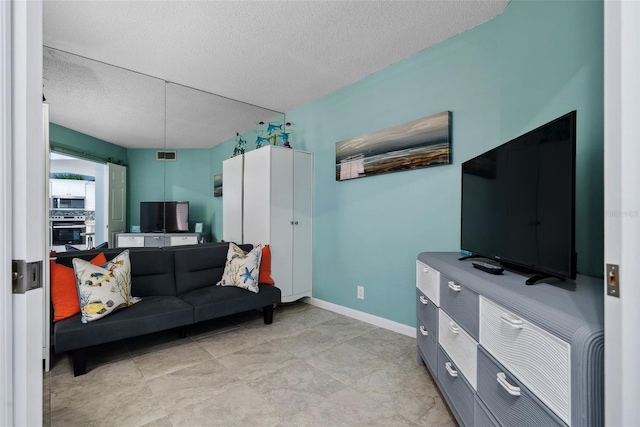 living area featuring visible vents, a textured ceiling, and baseboards