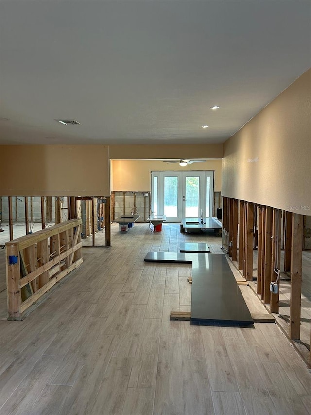 workout area with light hardwood / wood-style floors and french doors