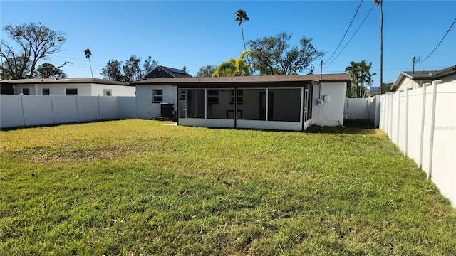 rear view of house with a sunroom, central AC unit, and a lawn