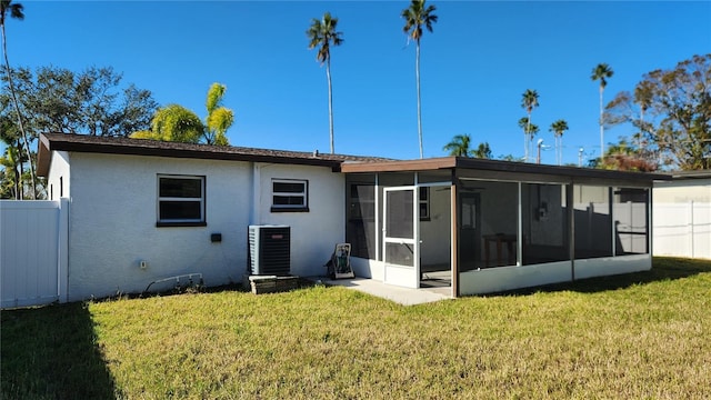 back of property with a yard, a sunroom, and central air condition unit