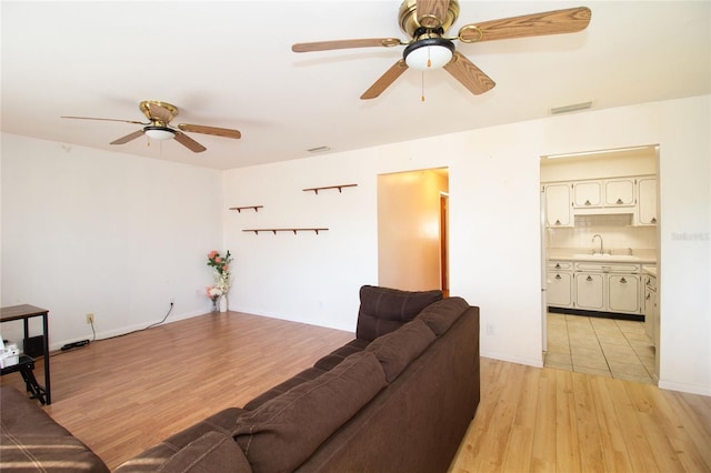 living room with ceiling fan, sink, and light wood-type flooring