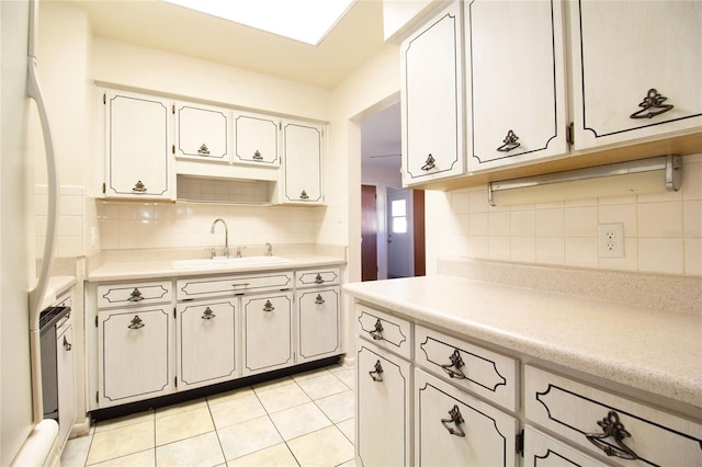 kitchen with fridge, sink, light tile patterned floors, and backsplash