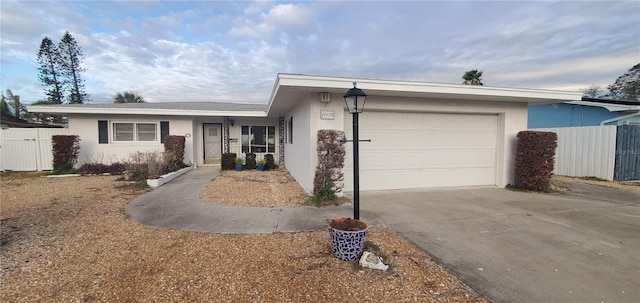 single story home with driveway, fence, an attached garage, and stucco siding