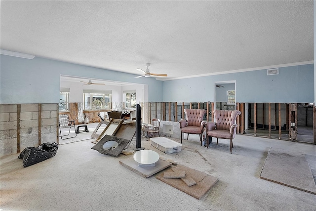 living room with ornamental molding, visible vents, ceiling fan, and a textured ceiling