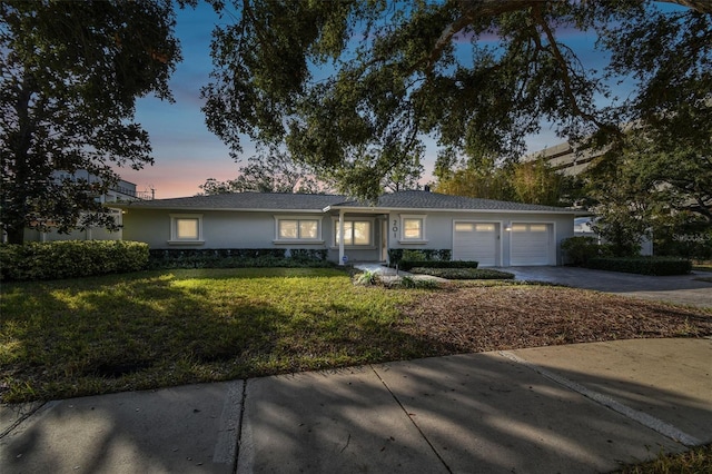 ranch-style home featuring a garage and a lawn