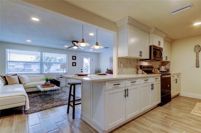 kitchen with electric stove, pendant lighting, white cabinetry, a kitchen breakfast bar, and kitchen peninsula