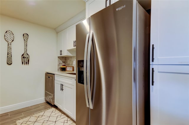 kitchen with appliances with stainless steel finishes, white cabinets, and backsplash