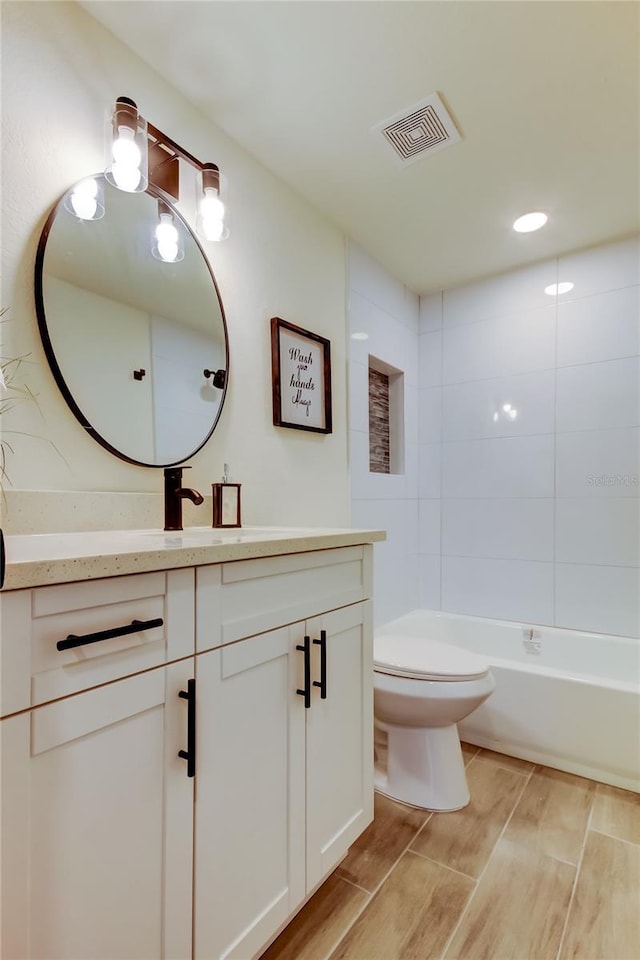 full bathroom featuring tiled shower / bath combo, vanity, and toilet