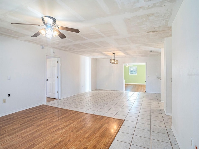 unfurnished room featuring ceiling fan with notable chandelier and light wood-type flooring