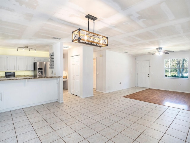 kitchen featuring pendant lighting, ceiling fan, white cabinetry, dark stone countertops, and stainless steel refrigerator with ice dispenser