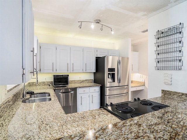 kitchen with stainless steel appliances, white cabinetry, light stone countertops, and sink