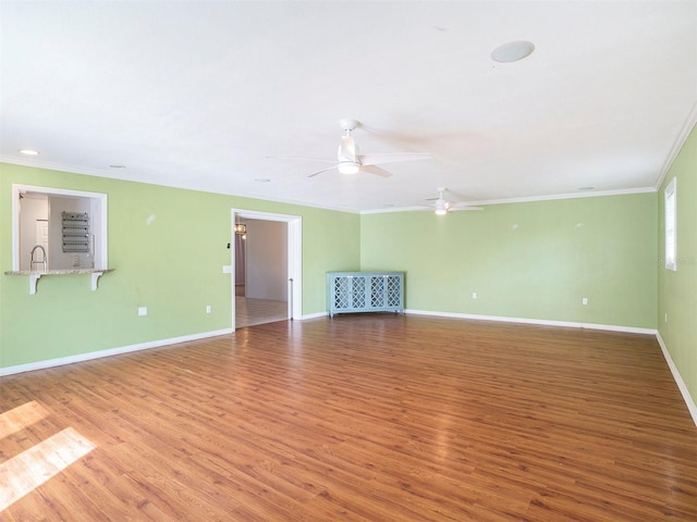 empty room with crown molding, wood-type flooring, and ceiling fan