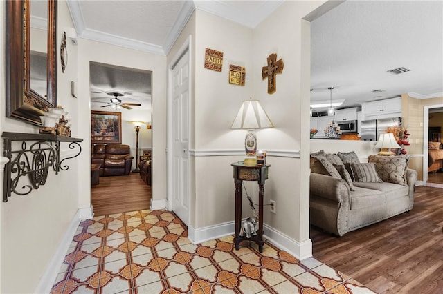 hallway featuring crown molding, light hardwood / wood-style floors, and a textured ceiling