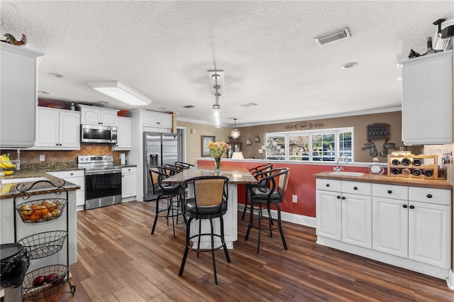 kitchen with appliances with stainless steel finishes, a breakfast bar area, hanging light fixtures, and white cabinets