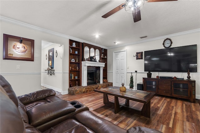 living room featuring a fireplace, wood-type flooring, ceiling fan, crown molding, and a textured ceiling