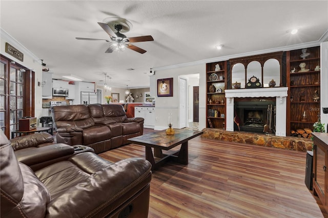 living room with ceiling fan, crown molding, a fireplace, and wood-type flooring