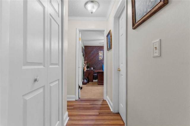 corridor featuring wood-type flooring, crown molding, a textured ceiling, and wood walls