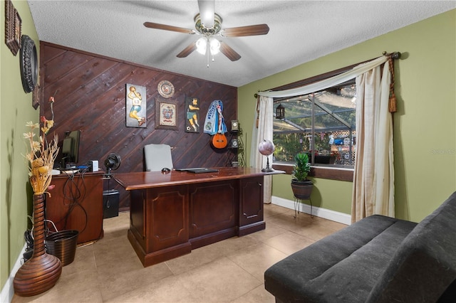 office space with light tile patterned floors, a textured ceiling, ceiling fan, and wood walls