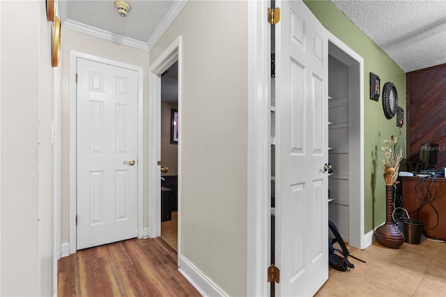 hallway with hardwood / wood-style flooring, ornamental molding, and a textured ceiling